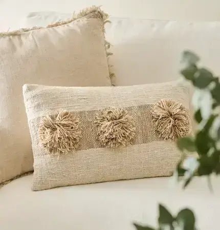 Textured pillow with pom-pom details on a light-colored sofa