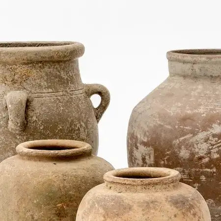 Four textured clay vases of different sizes with worn surfaces on a white background