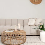 Beige channel-tufted modular sofa with a round woven rattan coffee table in a boho Dubai living room