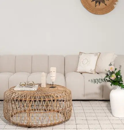 Beige channel-tufted modular sofa with a round woven rattan coffee table in a boho Dubai living room