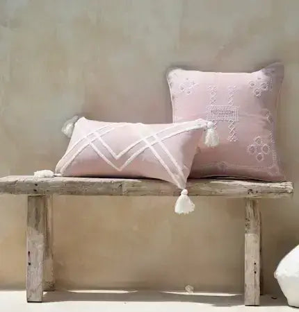 Blush pink boho cushion set with tassels on wooden bench