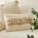 Textured pillow with pom-pom details on a light-colored sofa