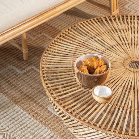 Close-up of a round rattan coffee table on a jute rug in boho decor