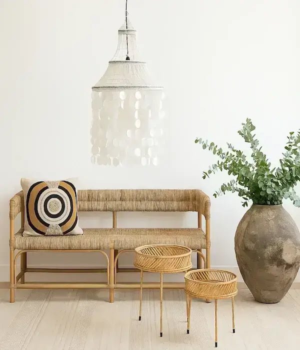 Rattan bench with decorative pillow, small tables and a large vase