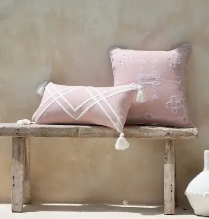 Handwoven decorative throw pillows in soft pink tones with embroidery and tassels, natural boho interior styling