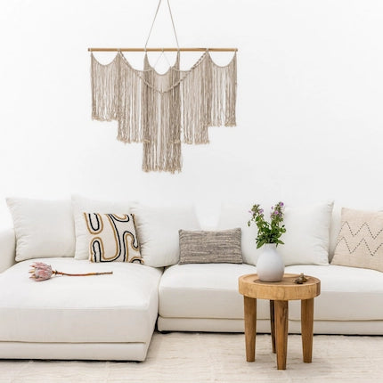 Macrame wall hanging above a white sofa with a wooden side table