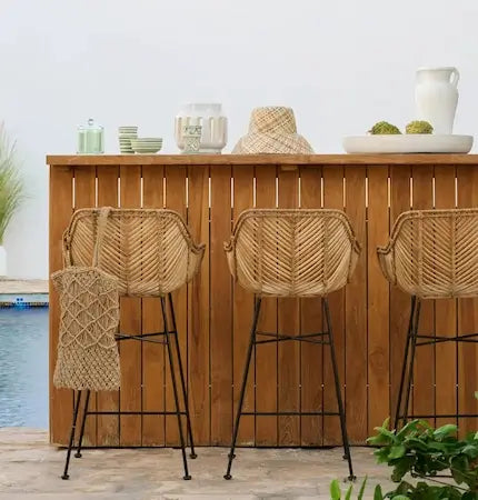 Rattan bar stools at a teak outdoor bar by the pool in Dubai