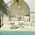 Rattan pendant light above arched seating nook with concrete side tables, neutral boho outdoor styling by the pool