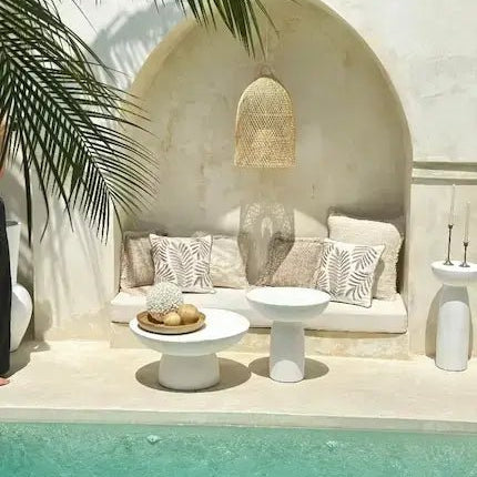 Rattan pendant light above arched seating nook with concrete side tables, neutral boho outdoor styling by the pool