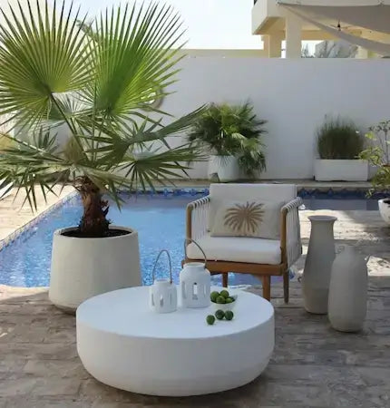 Round white concrete coffee table with lantern decor and limes by poolside, elegant boho outdoor styling in Dubai