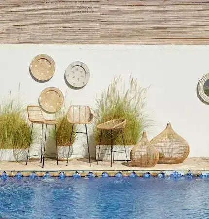 Stylish rattan bar stools and lights arranged by a sunny pool in Dubai style
