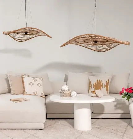 Two leaf-shaped rattan pendant lights over a boho living room sofa