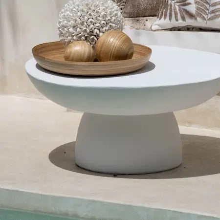 White outdoor concrete coffee table styled with a wooden tray and home decor