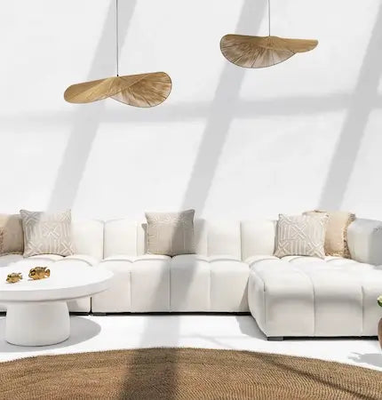 White channel-tufted modular sofa with throw pillows, jute pendant lights, and a round jute rug